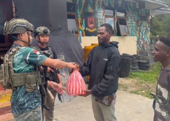 personel Satgas Ops Damai Cartenz Bharada Sahdan melaksanakan kegiatan humanis dengan membagikan sembako kepada warga di Distrik Paniai Timur, Kabupaten Pania, Senin (20/10/2025). (Dok. Puspen Ops Damai Cartenz)