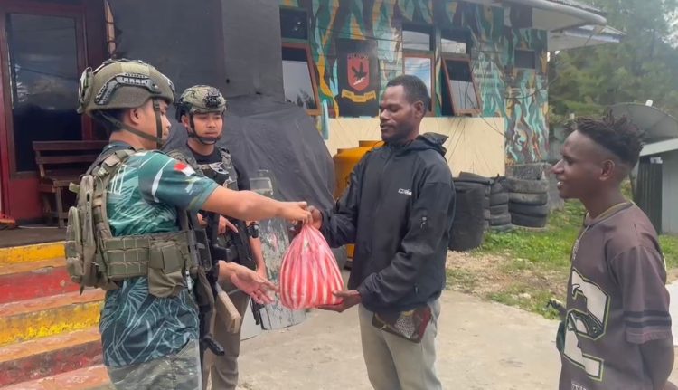 personel Satgas Ops Damai Cartenz Bharada Sahdan melaksanakan kegiatan humanis dengan membagikan sembako kepada warga di Distrik Paniai Timur, Kabupaten Pania, Senin (20/10/2025). (Dok. Puspen Ops Damai Cartenz)