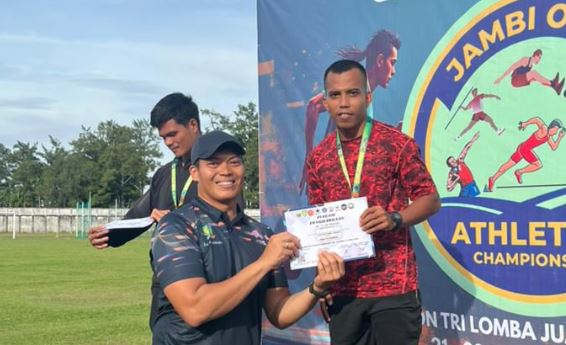 Ade Mardian Syahputra (kanan) menerima piagam penghargaan usai menjuarai nomor lari 100 meter dan 200 meter dalam Jambi Open Athletics Championship 2025 di Stadion Tri Lomba Juang KONI Jambi, Jumat (21/11/2025). (Dok. Daus)