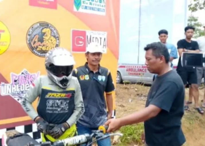 Ketua KONI Tanjab Timur Rustam Hasanuddin memberikan dukungan kepada pembalap muda Raffy Haidil sesaat sebelum tampil di ajang grasstrack memperebutkan Piala Bupati. (Dok. Daus)