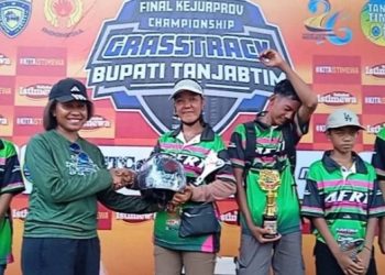 Kasat Lantas Polres Tanjab Timur Iptu Meiselin Lobat menyerahkan helm kepada salah satu rider Suku Anak Dalam (SAD) dari Adenan Family Racing Team sebagai bentuk dukungan keselamatan berkendara pada ajang Kejurprov Grasstrack Piala Bupati di Sabak Trail Circuit. (Dok. Daus)