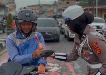 Seorang personel Satlantas Polresta Jambi memberikan cokelat kepada pengendara di Simpang Jelutung, Kota Jambi, dalam rangka peringatan Hari Guru Nasional 2025, Selasa (25/11/2025). (Dok, Nahar)