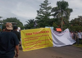 Warga membentangkan spanduk berisi tiga tuntutan saat menggelar aksi protes di depan kantor Pertamina EP Kenali Asam Bawah, Jambi, menolak penetapan zona merah yang dinilai merugikan pemilik tanah. Senin (24/11/2025), (Dok. Stepanus)