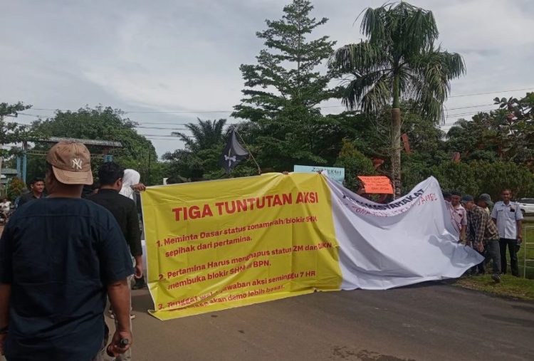Warga membentangkan spanduk berisi tiga tuntutan saat menggelar aksi protes di depan kantor Pertamina EP Kenali Asam Bawah, Jambi, menolak penetapan zona merah yang dinilai merugikan pemilik tanah. Senin (24/11/2025), (Dok. Stepanus)