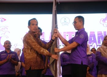 Asisten I Pemprov Jambi Arief Munandar menyerahkan bendera kepada Ketua IKA UNH Fiet Haryadi pada pelantikan pengurus IKA UNH di Rumah Dinas Gubernur Jambi, Kamis (27/11/2025).(dok.stepanus)