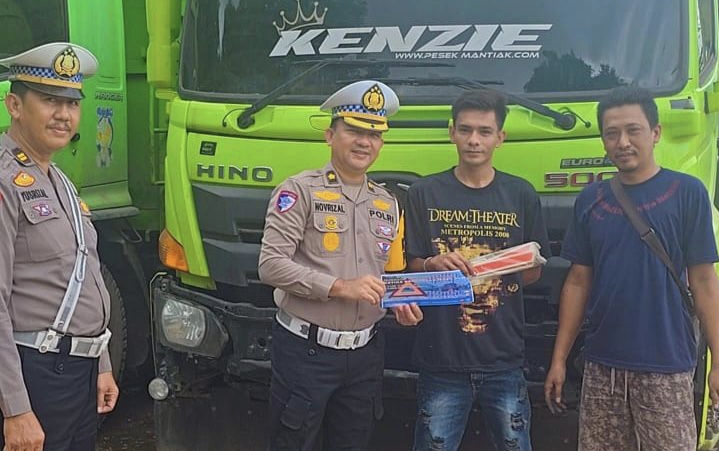 Kasatgas Preemtif Operasi Zebra Siginjai 2025 Kompol Dr. Novrizal menyerahkan perlengkapan segitiga pengaman kepada pengemudi truk saat pemeriksaan keselamatan di Terminal Barang Talang Gulo, Kota Jambi, Jumat (21/11/2025).(Dok.Nahar)