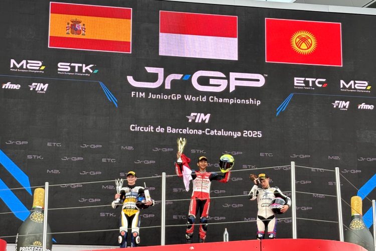 Pebalap muda Indonesia M. Kiandra Ramadhipa mengibarkan bendera Merah Putih di podium tertinggi usai menjuarai European Talent Cup (ETC) FIM JuniorGP 2025 di Circuit de Barcelona-Catalunya, Spanyol, Minggu (2/11/2025). (Dok. Sisnsen)