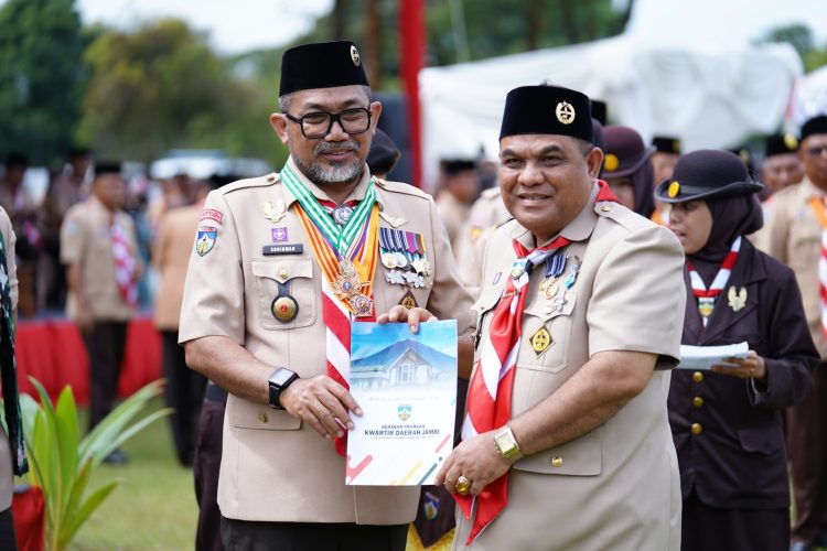 Sekda Provinsi Jambi, Sudirman, menerima buku laporan Gerakan Pramuka Kwartir Daerah Jambi dalam rangkaian Apel Besar Hari Pramuka ke-64 di Tanjung Jabung Timur, Rabu (19/11/2025). (Dok. Daus)