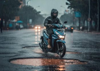 Ilustarsi pengendara sepeda motor melintasi jalan berlubang di tengah hujan deras. (Dok. Sinsen)