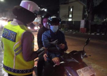 Personel Satlantas Polda Jambi memberikan imbauan kepada pengendara motor saat sosialisasi Operasi Zebra Siginjai 2025 di kawasan Simpang Jelutung, Kota Jambi, Sabtu malam (22/11/2025). (Dok. Nahar)