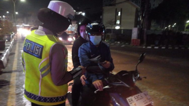 Personel Satlantas Polda Jambi memberikan imbauan kepada pengendara motor saat sosialisasi Operasi Zebra Siginjai 2025 di kawasan Simpang Jelutung, Kota Jambi, Sabtu malam (22/11/2025). (Dok. Nahar)