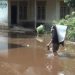 Seorang warga menggendong barang melintasi banjir yang menggenangi permukiman di Desa Kota Baru, Kecamatan Geragai, Kabupaten Tanjung Jabung Timur, akibat hujan deras dan pendangkalan sungai. (Dok. Daus)