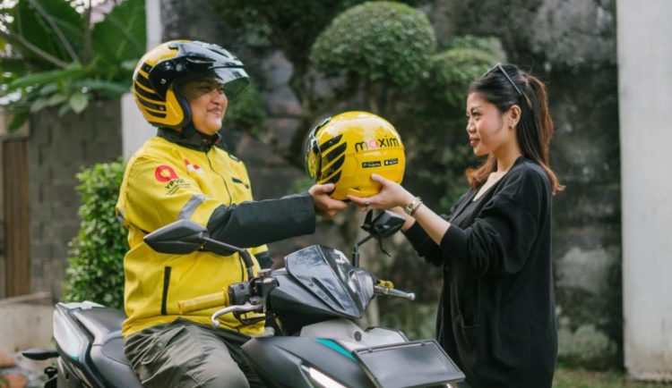 Seorang pengemudi Maxim menyerahkan helm kepada penumpang sebelum memulai perjalanan. Layanan transportasi daring Maxim kini resmi beroperasi di Danau Kerinci dan Bangko, Jambi. (Dok. MAXIM)