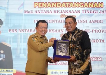 Gubernur Jambi Al Haris dan perwakilan Kejaksaan Tinggi Jambi bertukar cenderamata usai penandatanganan MoU pelaksanaan pidana kerja sosial di Auditorium Rumah Dinas Gubernur Jambi, Selasa (2/12/2025). (Dok. Daus)