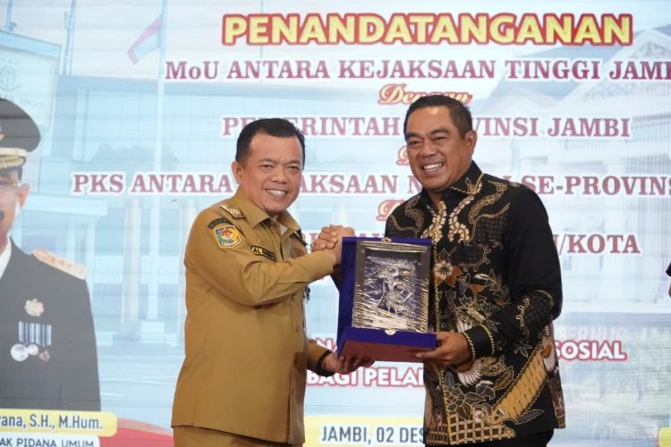 Gubernur Jambi Al Haris dan perwakilan Kejaksaan Tinggi Jambi bertukar cenderamata usai penandatanganan MoU pelaksanaan pidana kerja sosial di Auditorium Rumah Dinas Gubernur Jambi, Selasa (2/12/2025). (Dok. Daus)