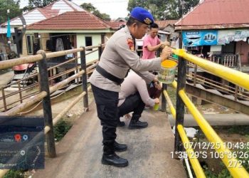 Personel Ditpolairud Polda Jambi bersama warga melakukan pengecatan jembatan penghubung Kampung Pulau Pandan menuju Pasar Angso Duo, Minggu (7/12/2025). (Dok. Nahar)