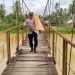 Kapolsek Limun AKP Berlin Tarigan bersama personel kepolisian dan warga mengangkat papan kayu untuk memperbaiki jembatan gantung di Desa Muara Limun, Kecamatan Limun, Kabupaten Sarolangun, Rabu (17/12/2025).-(Dok. Humas)