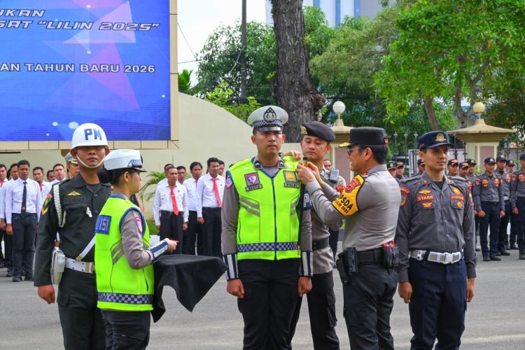 Kapolda Jambi Irjen Pol Krisna H. Siregar menyematkan pita tanda dimulainya Operasi Lilin 2025 kepada perwakilan personel dalam Apel Gelar Pasukan di Mapolda Jambi, Jumat (19/12/2025). (Dok. Nahar)