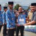 Bupati Kerinci Monadi, S.Sos., M.Si. menyerahkan SK PPPK Paruh Waktu Formasi Tahun 2025 kepada perwakilan penerima di Lapangan Kantor Bupati Kerinci, Minggu (21/12/2025). (Dok. Deko)