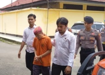 Petugas Satreskrim Polres Tanjung Jabung Timur mengawal tersangka kasus dugaan penipuan dana ibadah haji dengan kerugian Rp235 juta saat proses penanganan perkara di Mapolres Tanjab Timur. (Dok. Daus)