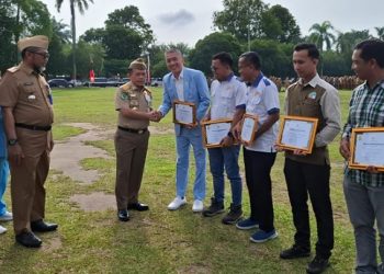 Gubernur Jambi Al Haris menyerahkan penghargaan kepada perwakilan perusahaan dalam Upacara Peringatan Bulan Keselamatan dan Kesehatan Kerja (K3) yang dirangkaikan dengan Apel Kesadaran Nasional ASN di Lapangan Kantor Gubernur Jambi, Senin (19/1/2026). (Dok. Stepanus)