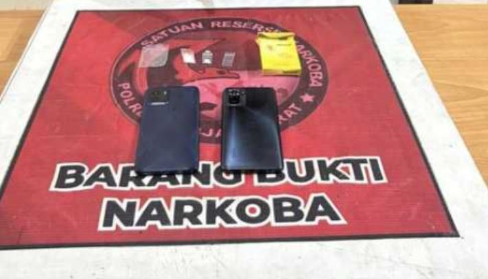 Barang bukti kasus narkotika yang diamankan polisi dari tersangka SN, terdiri atas dua unit telepon genggam, kotak rokok, dan uang tunai, saat pelimpahan perkara ke Satresnarkoba Polres Tanjung Jabung Barat. (Dok. Humas)