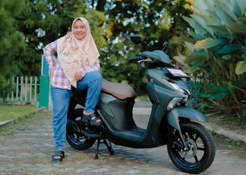 Seorang pengguna berpose bersama Yamaha Gear Ultima yang digunakan untuk menunjang aktivitas harian di Jambi, termasuk melintasi jalan dengan kondisi beragam, Senin (13/1/2026). (Dok. Yamaha)