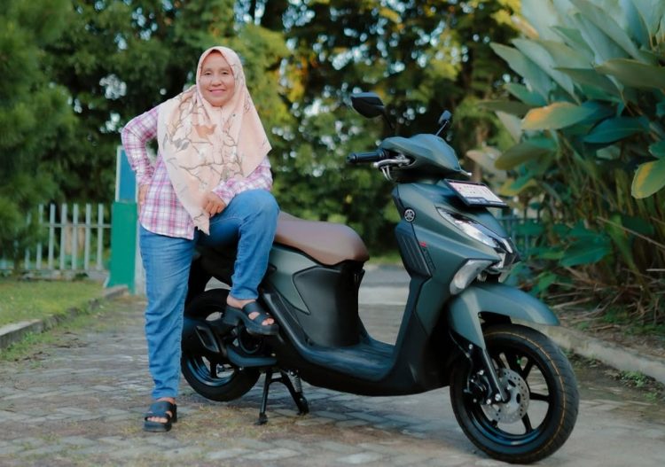 Seorang pengguna berpose bersama Yamaha Gear Ultima yang digunakan untuk menunjang aktivitas harian di Jambi, termasuk melintasi jalan dengan kondisi beragam, Senin (13/1/2026). (Dok. Yamaha)