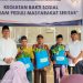 Kepala LPKA Kelas II Muara Bulian J. Kasogi Surya Fattah bersama jajaran pegawai menyerahkan paket sembako kepada warga saat kegiatan bakti sosial “IMIPAS Peduli Masyarakat Sekitar” di Muara Bulian, Jumat (13/3/2026). (Dok. Humas)