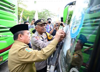 Gubernur Al Haris menempelkan stiker di kendaraan saat pelepasan peserta mudik gratis dalam rangka pencanangan Angkutan Lebaran Terpadu 2026 di Terminal Tipe A Alam Barajo, Sabtu (14/3/2026). (Dok. Nahar)
