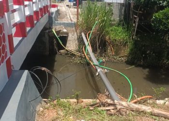 Kabel jaringan milik Telkom Indonesia menjuntai dan semrawut di Jembatan Air Cugung Patil. (Foto:Yl)
