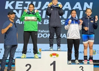 Lifter putri Jambi Juliana Klarisa (tengah) berdiri di podium juara usai meraih tiga medali emas pada Kejuaraan Nasional Angkat Besi Senior Pupuk Indonesia 2026 di Bandung, Jawa Barat. (Dok, Nanang)