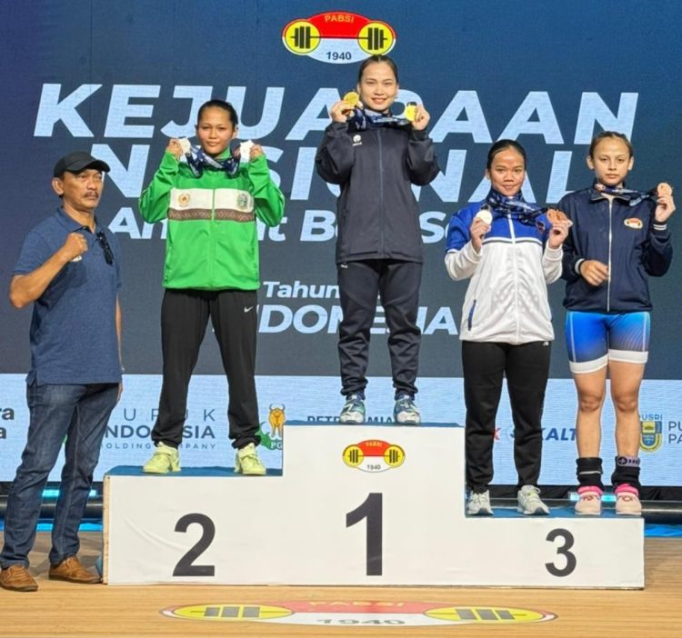 Lifter putri Jambi Juliana Klarisa (tengah) berdiri di podium juara usai meraih tiga medali emas pada Kejuaraan Nasional Angkat Besi Senior Pupuk Indonesia 2026 di Bandung, Jawa Barat. (Dok, Nanang)